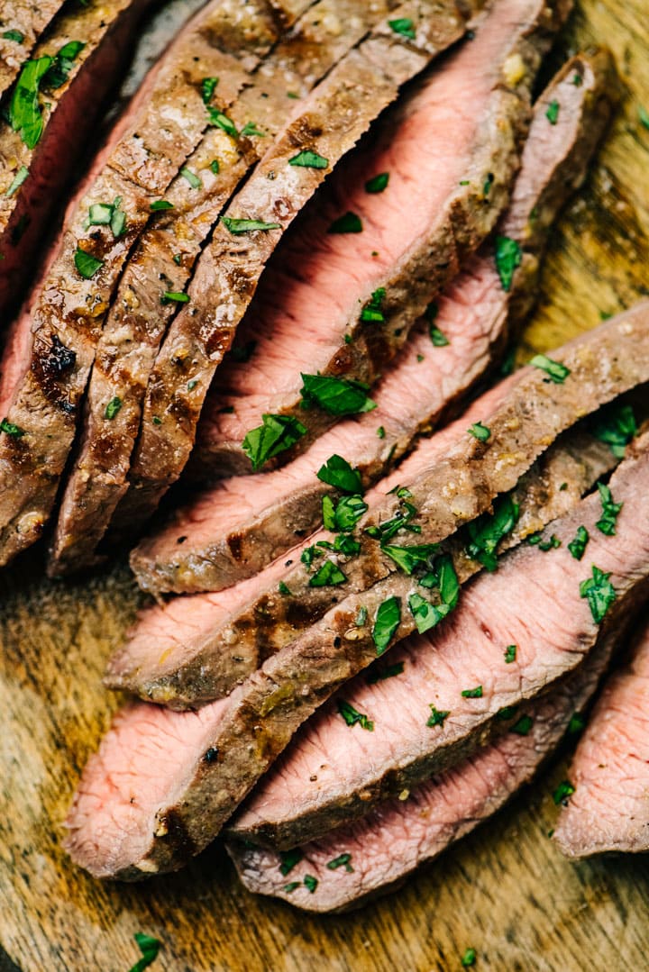 Thin slices of grilled flat iron steak on a cutting board.