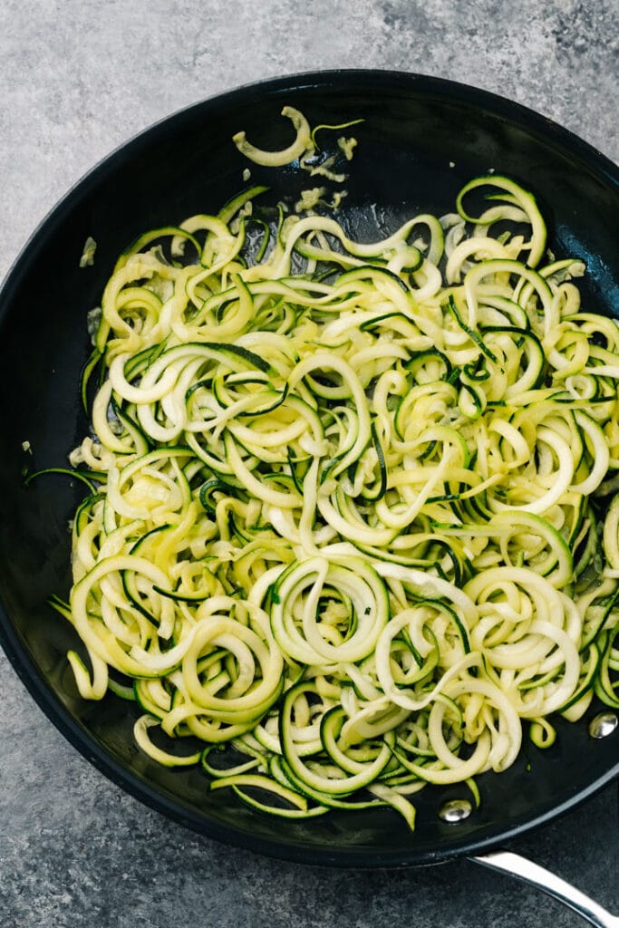 Sautéed zucchini noodles in a skillet.