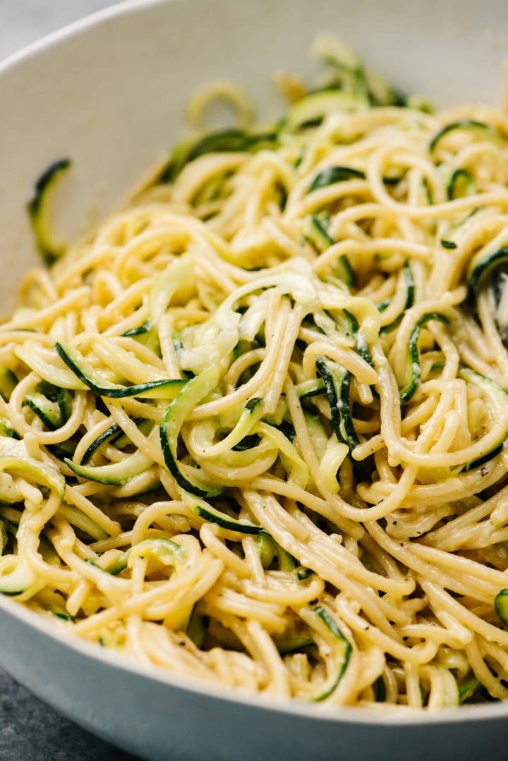 Side view, zucchini pasta with zoodles in a large white serving bowl.