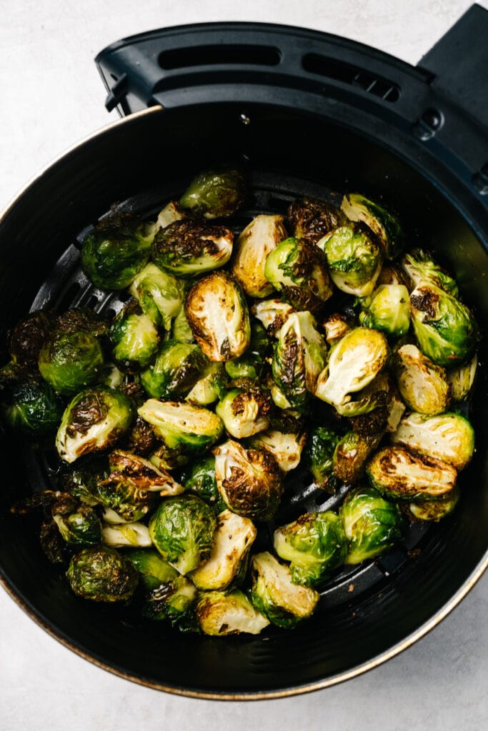 Roasted brussels sprouts in the basket of an air fryer.