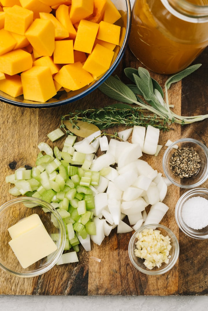 The ingredients for instant pot butternut squash soup arranged on a cutting board.
