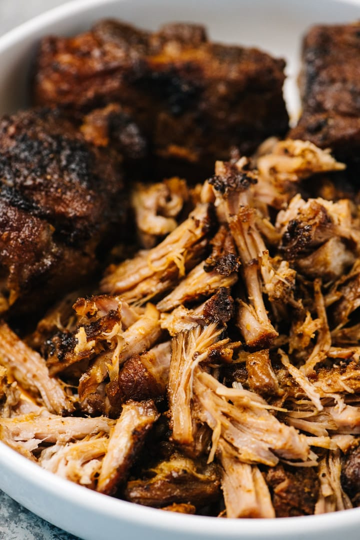 Side view, partially shredded pulled pork in a white serving bowl.