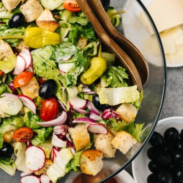 Large tossed italian salad in a glass mixing bowl with homemade croutons.