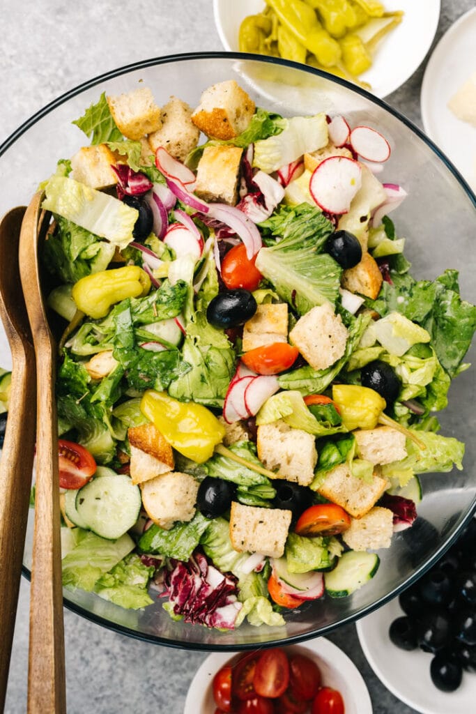 Homemade croutons stirred into an italian salad in a large glass mixing bowl.