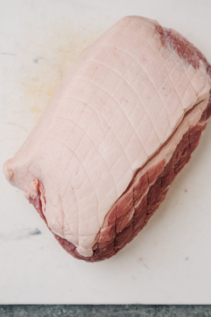 Boneless pork butt on a white cutting board showing fat cap. 