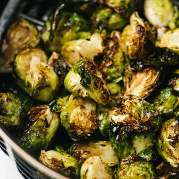 Side view, crispy brussels sprouts in the basket of an air fryer.