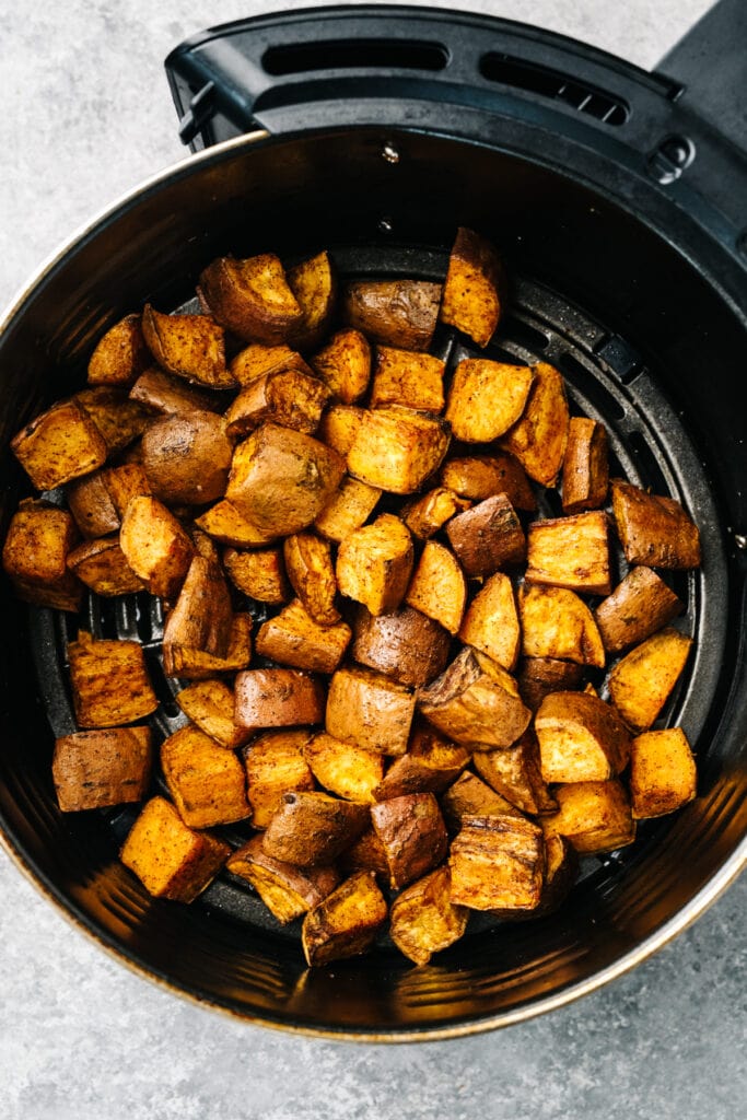 Crispy roasted air fried sweet potato cubes in an air fryer basket.