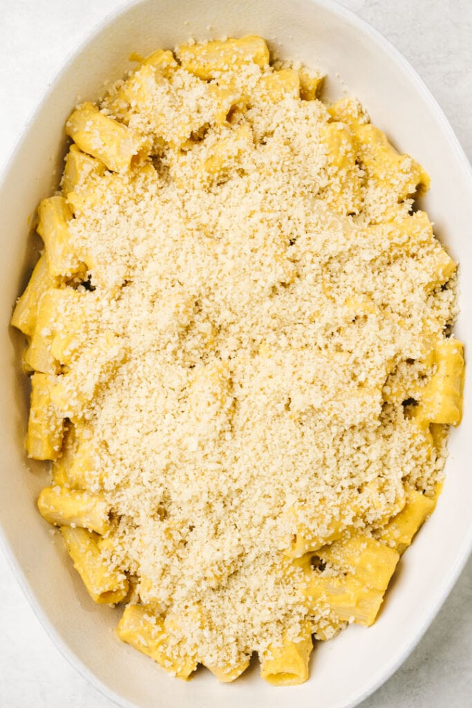Butternut squash mac and cheese in a casserole dish sprinkled with breadcrumbs.