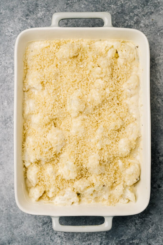 An unbaked cauliflower au gratin casserole topped with panko breadcrumbs.