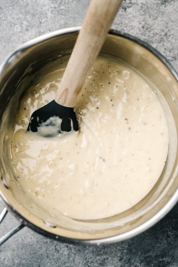 Cheesy bechameal sauce in a saucepot for making cauliflower au gratin.