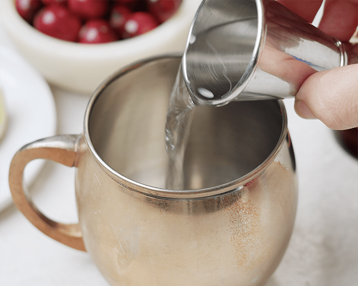 Pouring vodka into a copper mug.