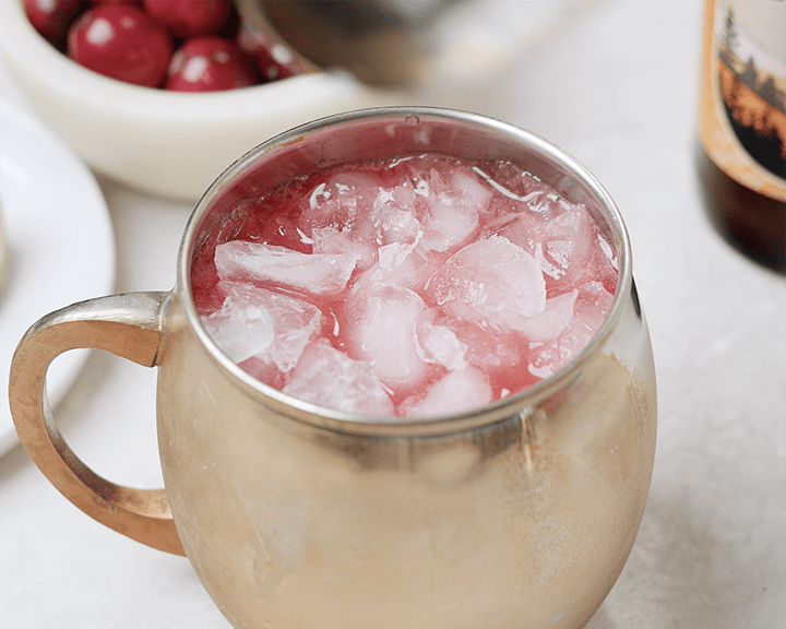 A cranberry moscow mule topped with lots of crushed ice before garnishing.