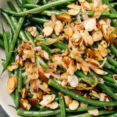 Green beans almondine (green beans with almonds) in a tan serving bowl.
