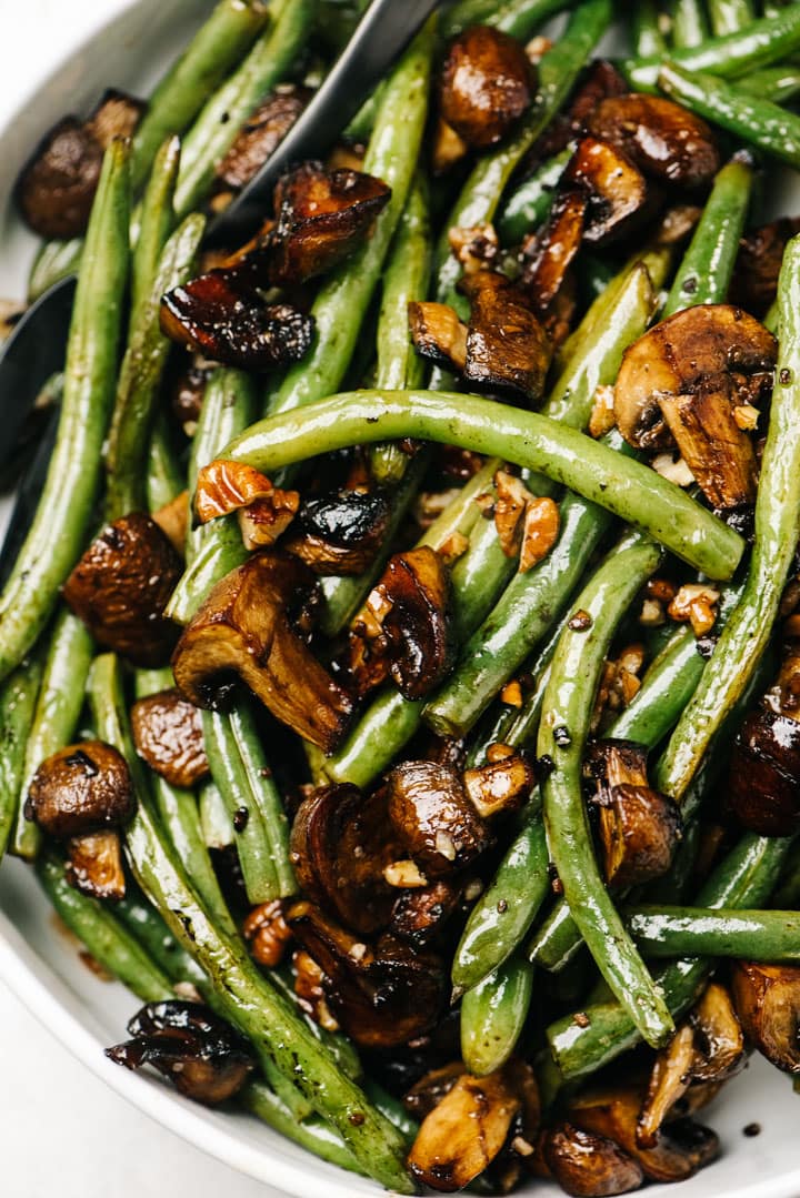 Roasted green beans and mushrooms in a white serving bowl.