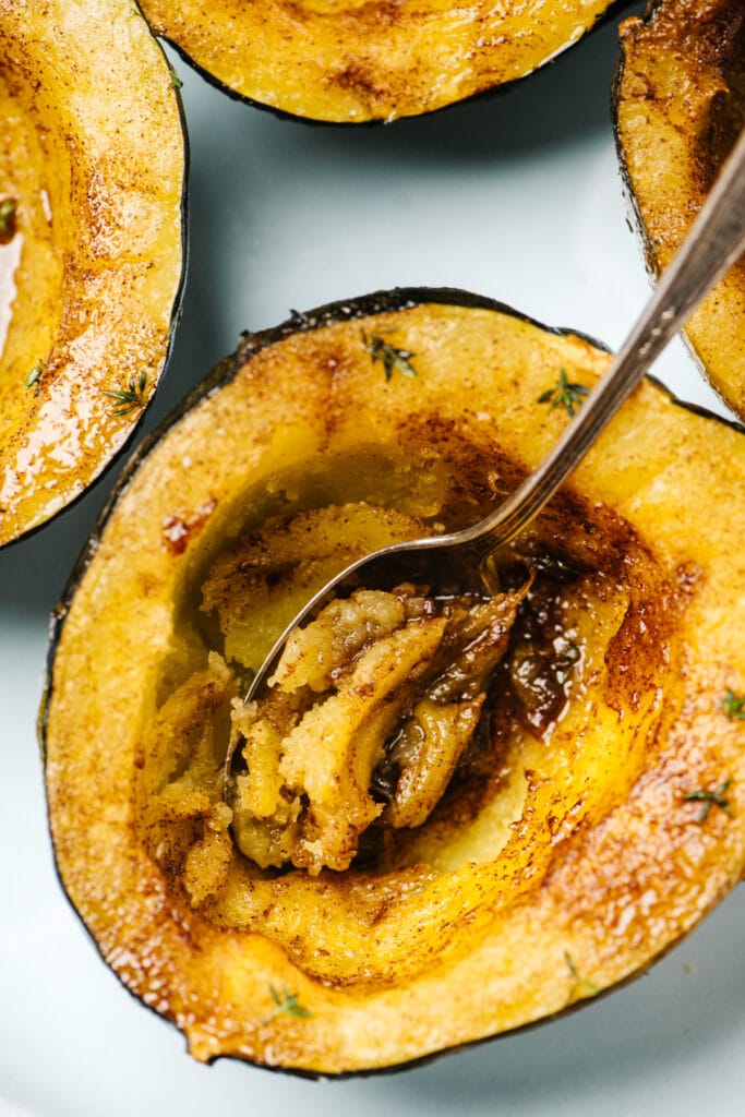 Several instant pot acorn squash halves on a blue plate, drizzled with butter and brown sugar.