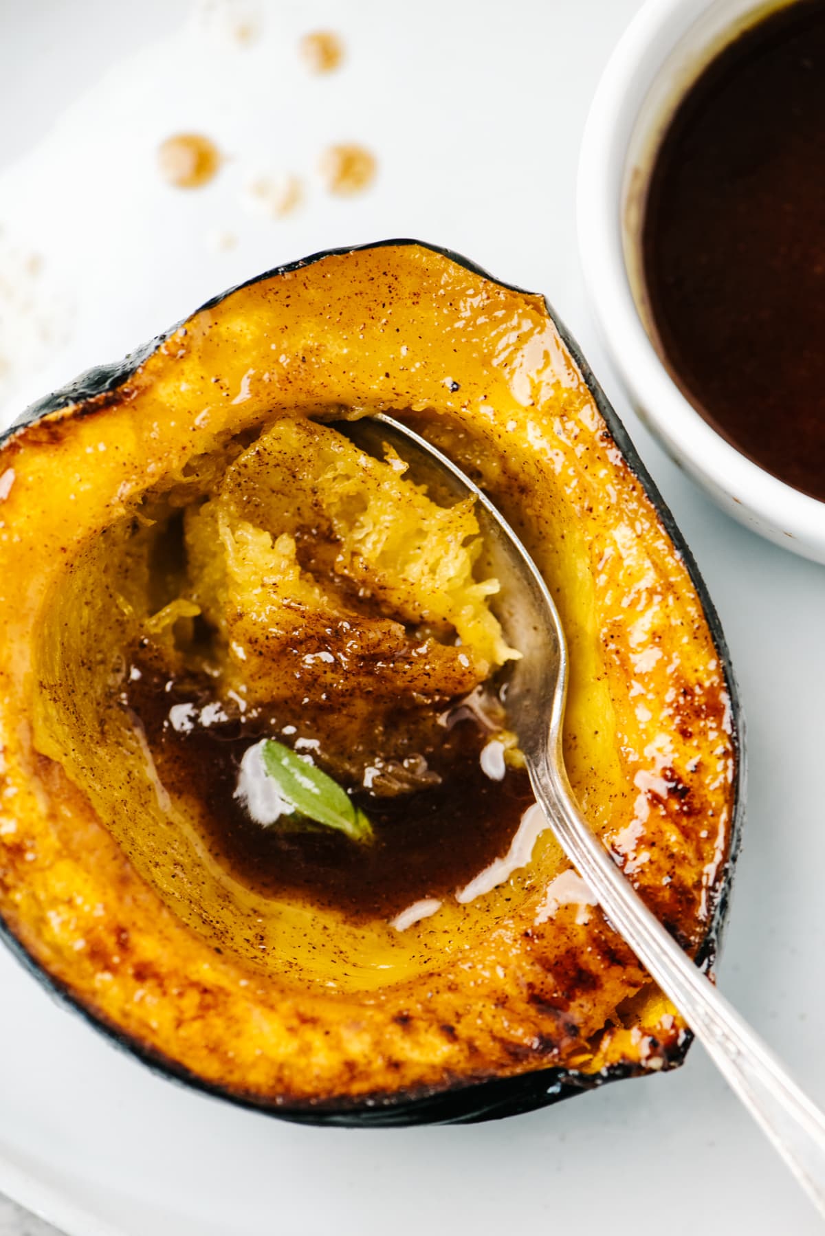 A spoon tucked into a roasted acorn squash half on a white plate.