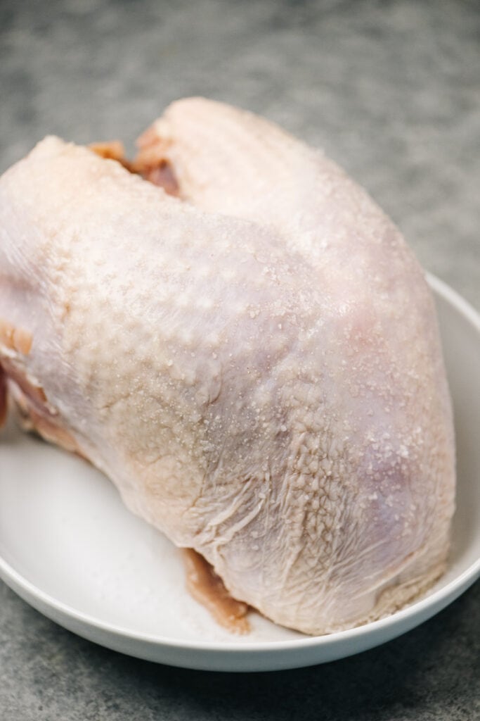 Side view, a turkey breast sprinkled with salt for a dry brine.