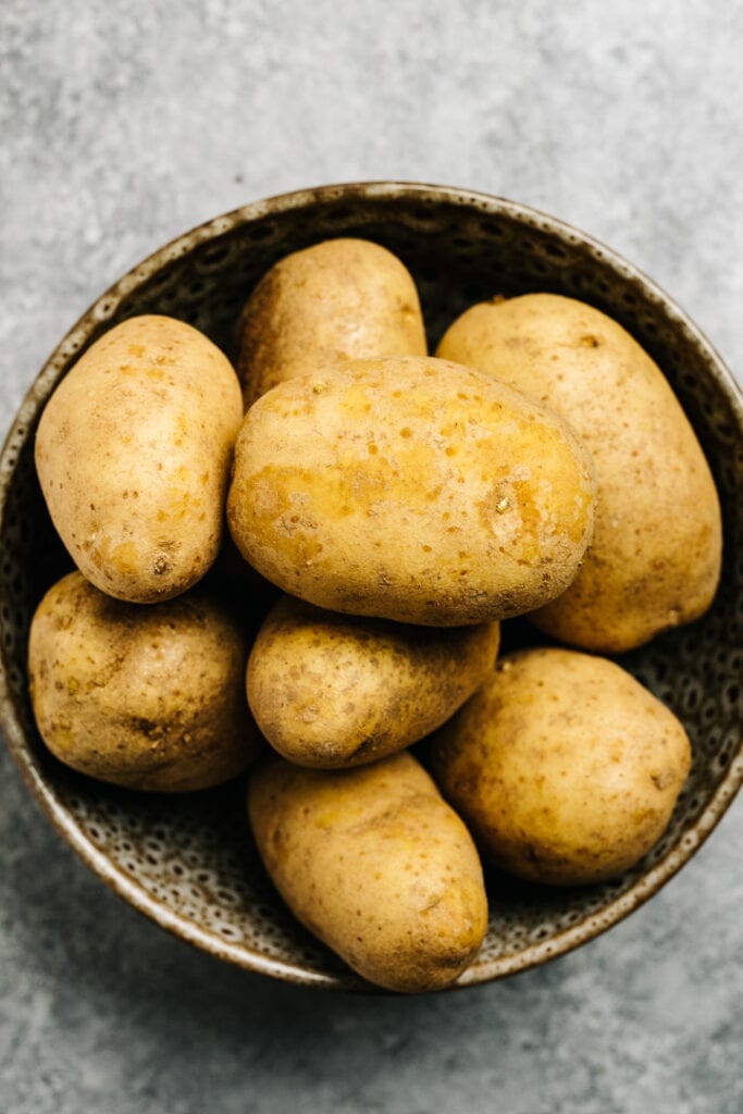Russet potatoes in a tan speckled serving bowl.