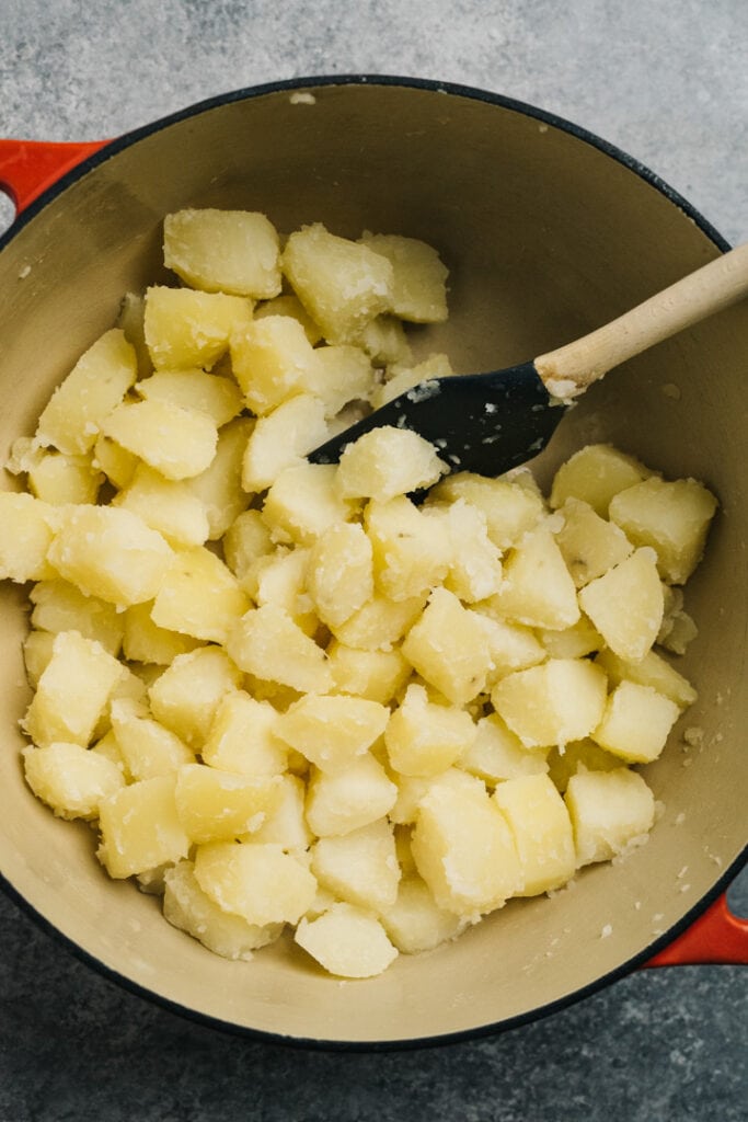 Cooked diced potatoes drained and return to a hot pot to dry off completely.