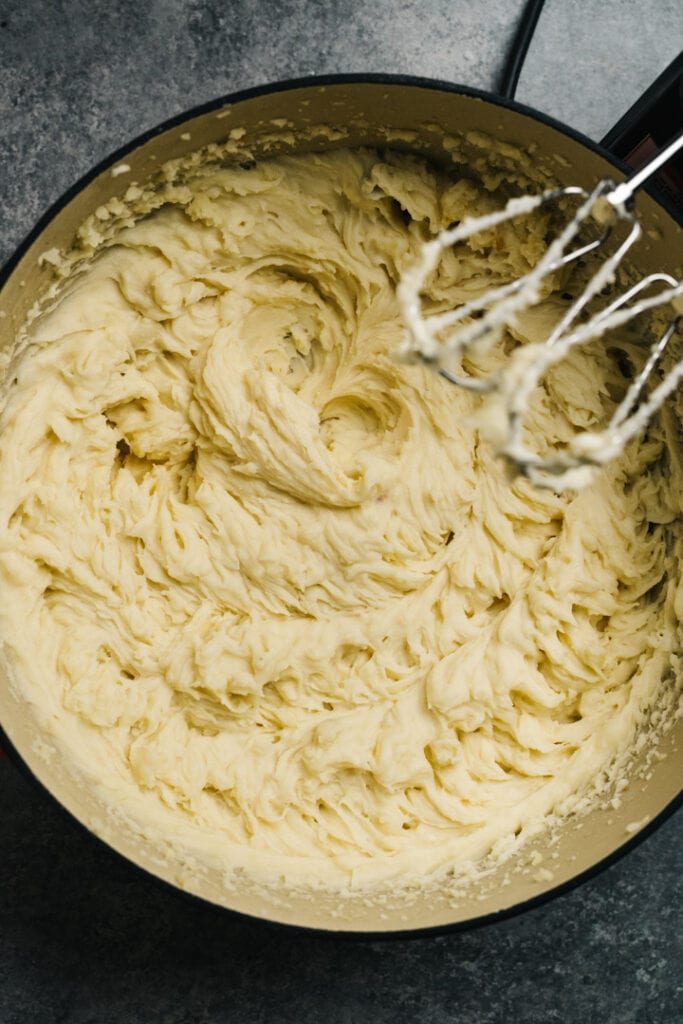 Roasted garlic mashed potatoes just after mashing in a red dutch oven.