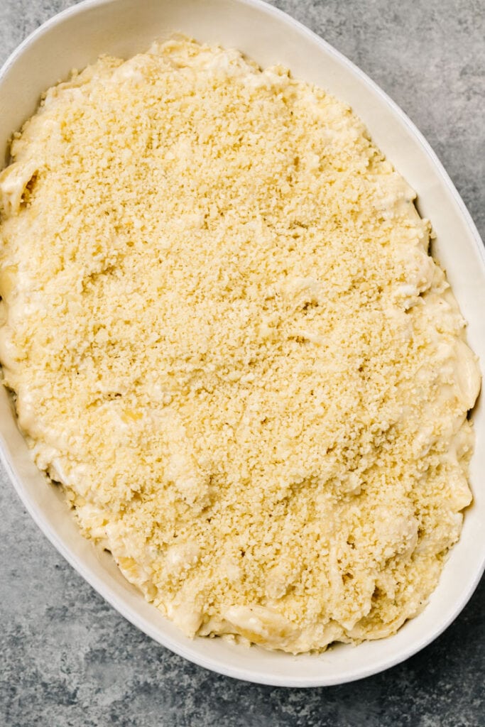 Crab mac and cheese in a casserole dish topped with buttery breadcrumbs before baking.