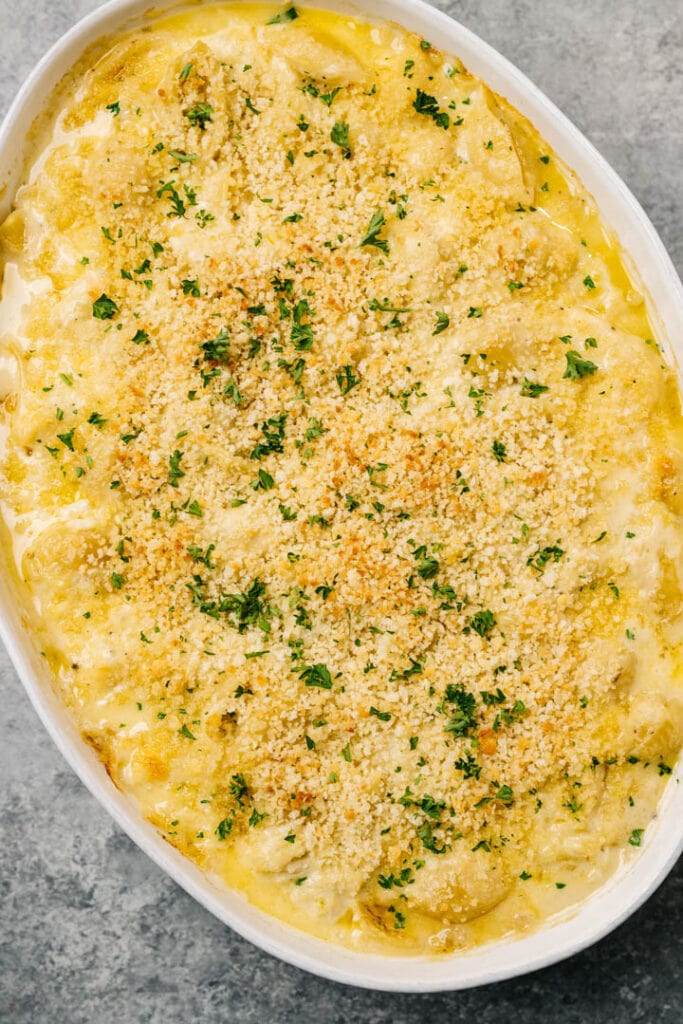 Baked Crab mac and cheese in a white oval dutch oven, garnished with chopped parsley.