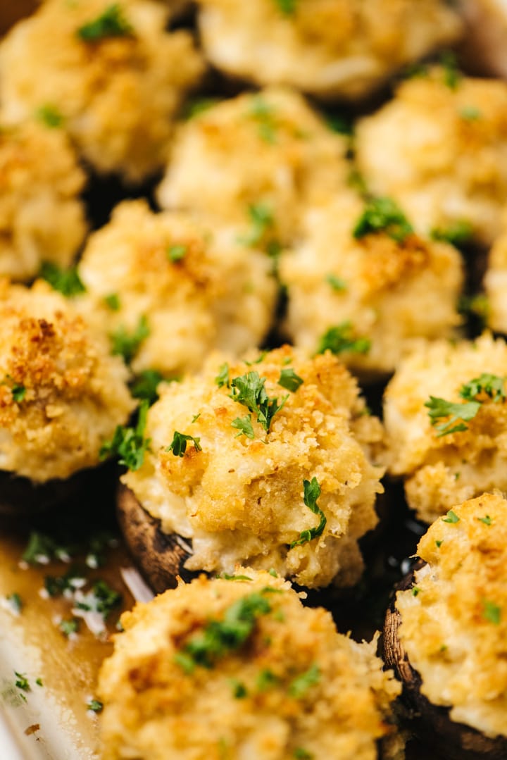 Side view, crab stuffed mushrooms in a casserole dish, garnished with chopped parsley.