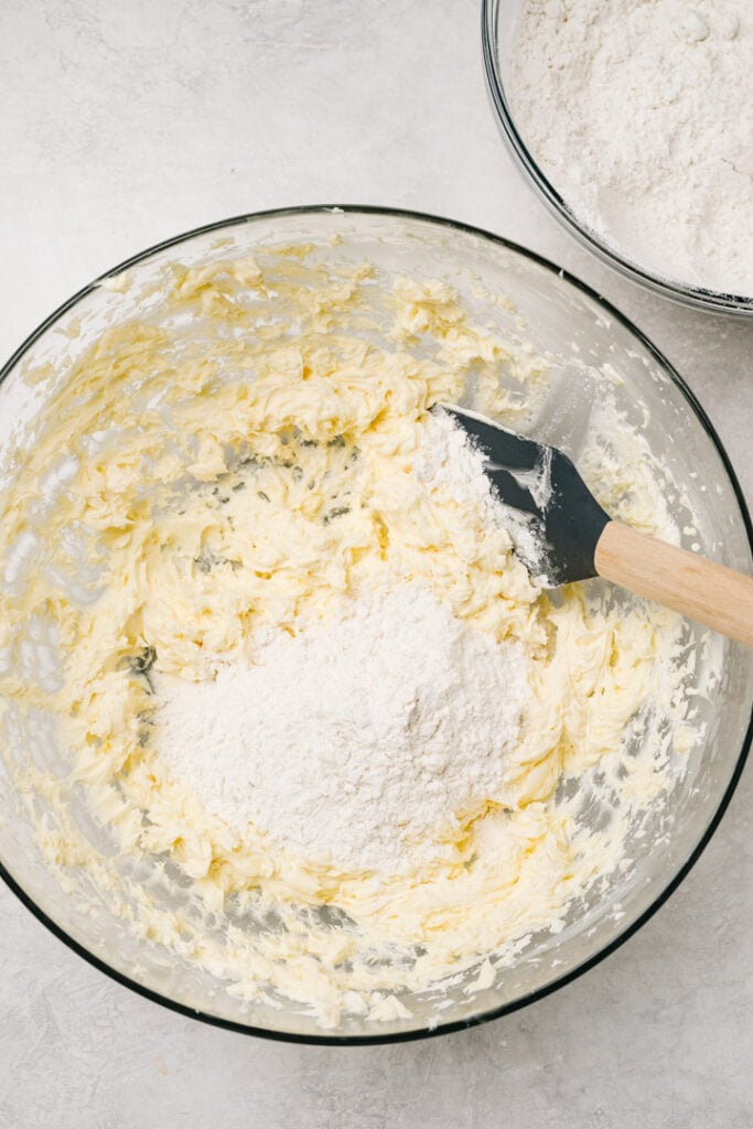 Adding gluten free flour in batches to creamed butter, sugar, and egg mixture.