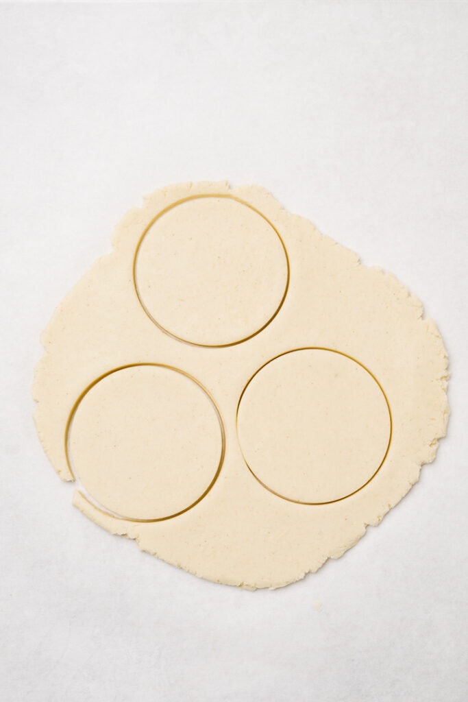 Rolled out gluten free sugar cookie dough with three cookies cut-out.