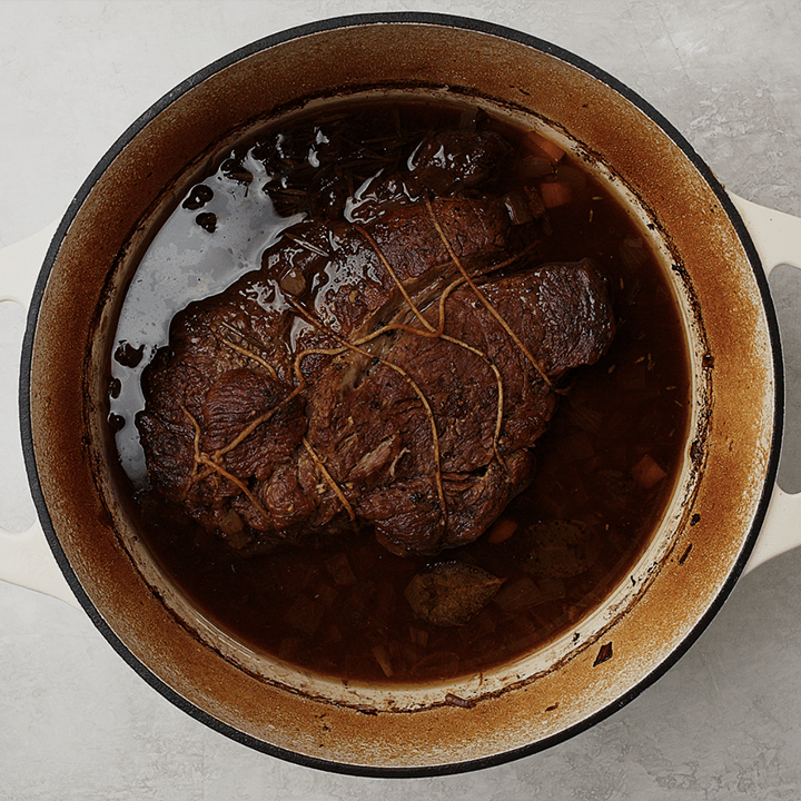 A braised red wine pot roast in a dutch oven after braising.