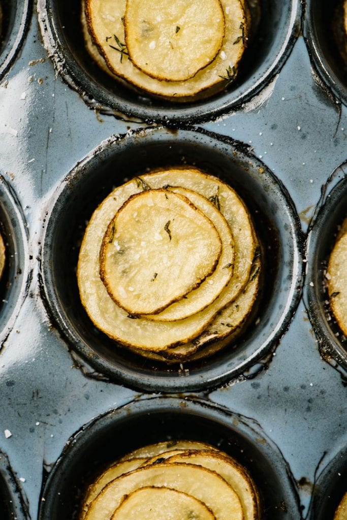 Crispy herb potato stacks in a muffin tin.