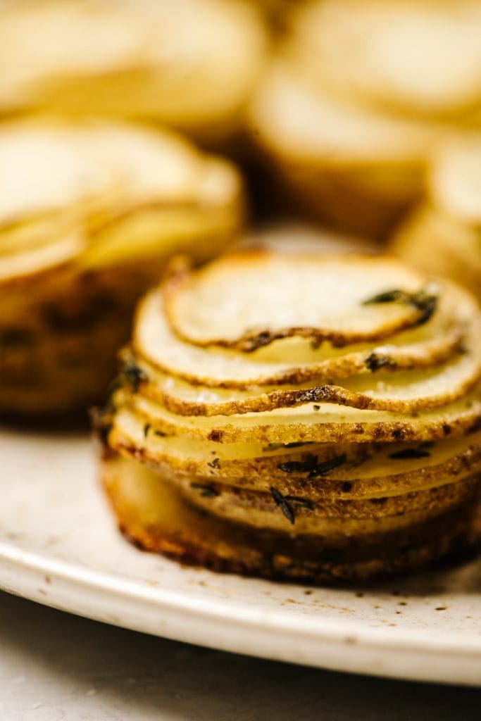 Side view, crispy potato stacks on a speckled tan serving platter.