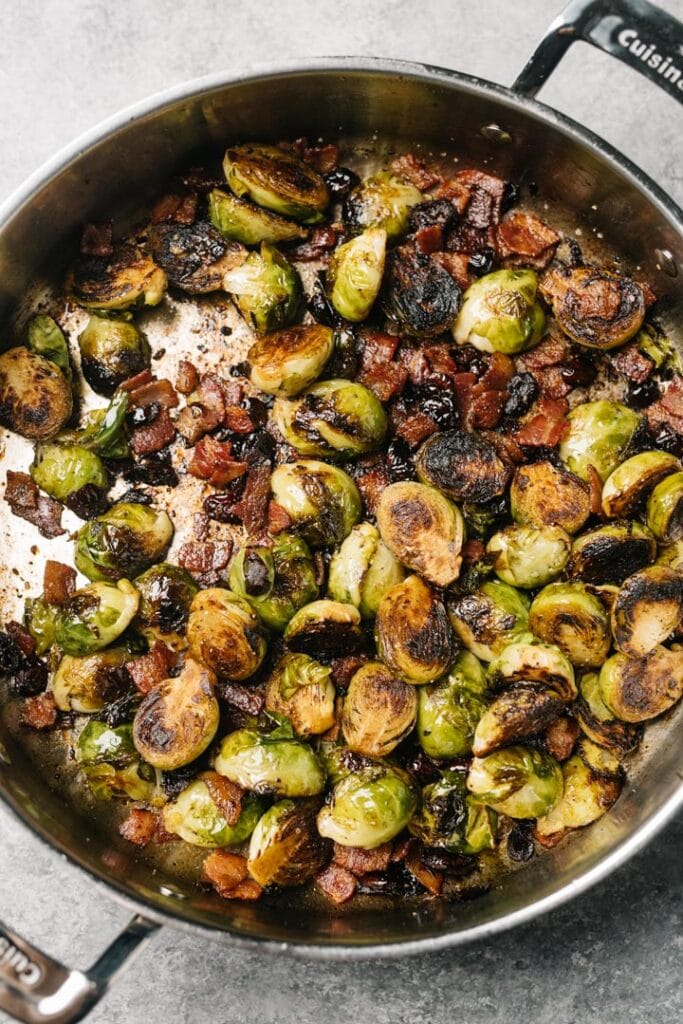 Sauteed brussels sprouts with bacon, cranberries, and balsamic vinegar in a large skillet.