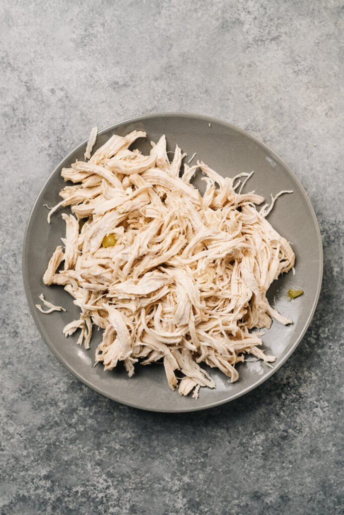 Shredded chicken on a grey plate on a concrete background.