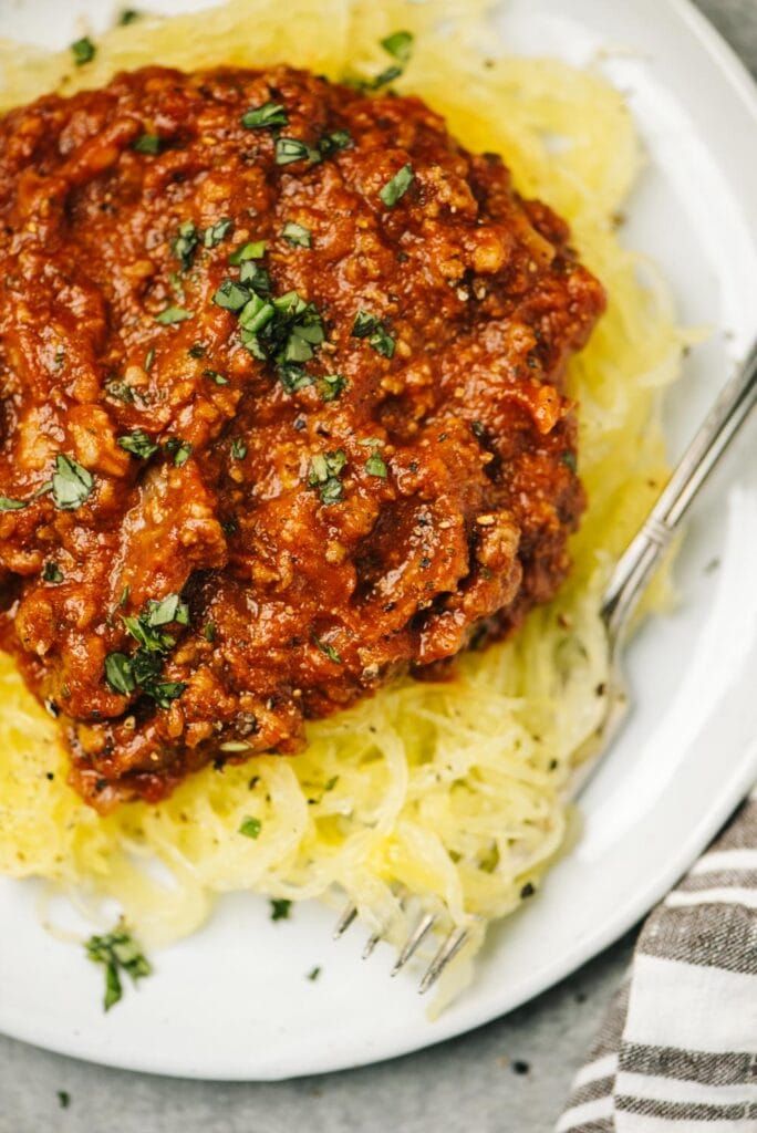 Spaghetti squash spaghetti with italian meat sauce on a white plate with a vintage silver fork.