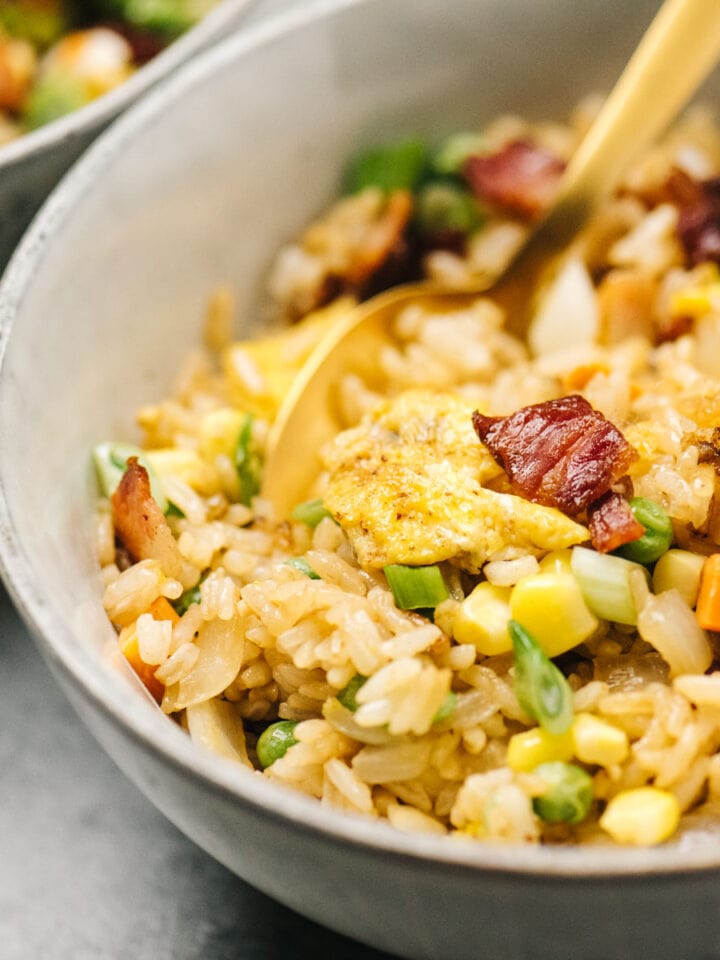 Side view, breakfast fried rice in a bowl with a gold spoon.