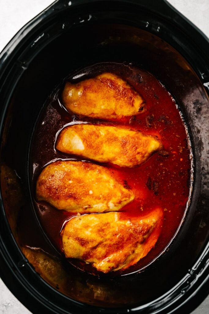 Cooked buffalo chicken breasts in a crockpot.