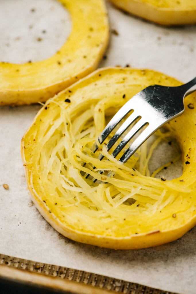 Side view, separating spaghetti squash flesh into "noodles" using a fork.