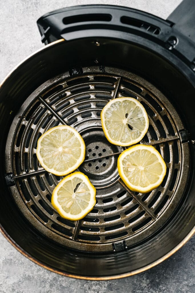 Four lemon slices in the basket of an air fryer.