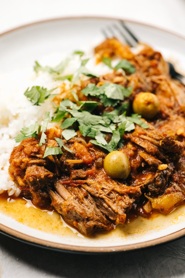 Side view, slow cooker ropa vieja over white rice with lots of fresh cilantro.
