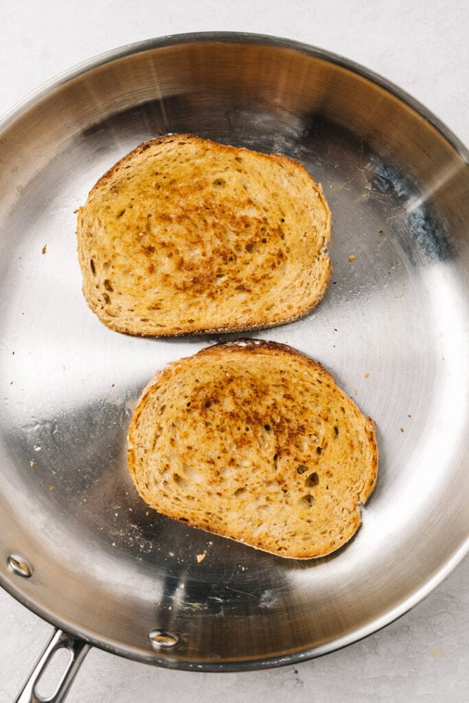 Slices of bread toasting in a skillet.