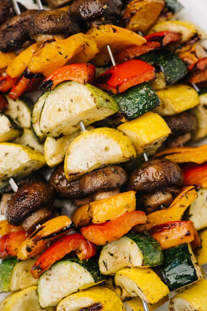 Grilled vegetable kebabs stacked on a plate.