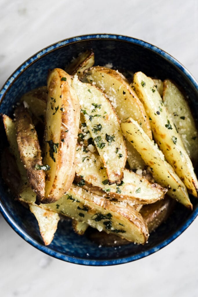 Hand cut basil fries in a blue serving bowl.