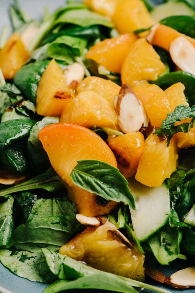 Side view, grilled peach salad with fresh basil and toasted almonds.