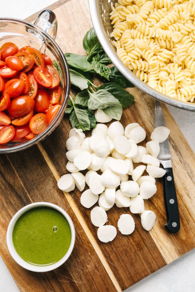 Caprese pasta salad ingredients on a cutting board.