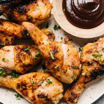 Grilled chicken legs with a dipping sauce.