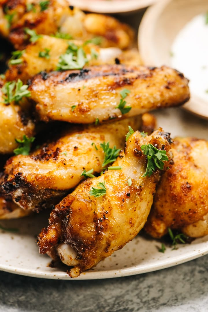 Side view, close up of crispy grilled wings topped with fresh herbs. 