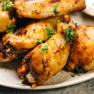 Crispy grilled chicken wings on a plate with fresh herbs.