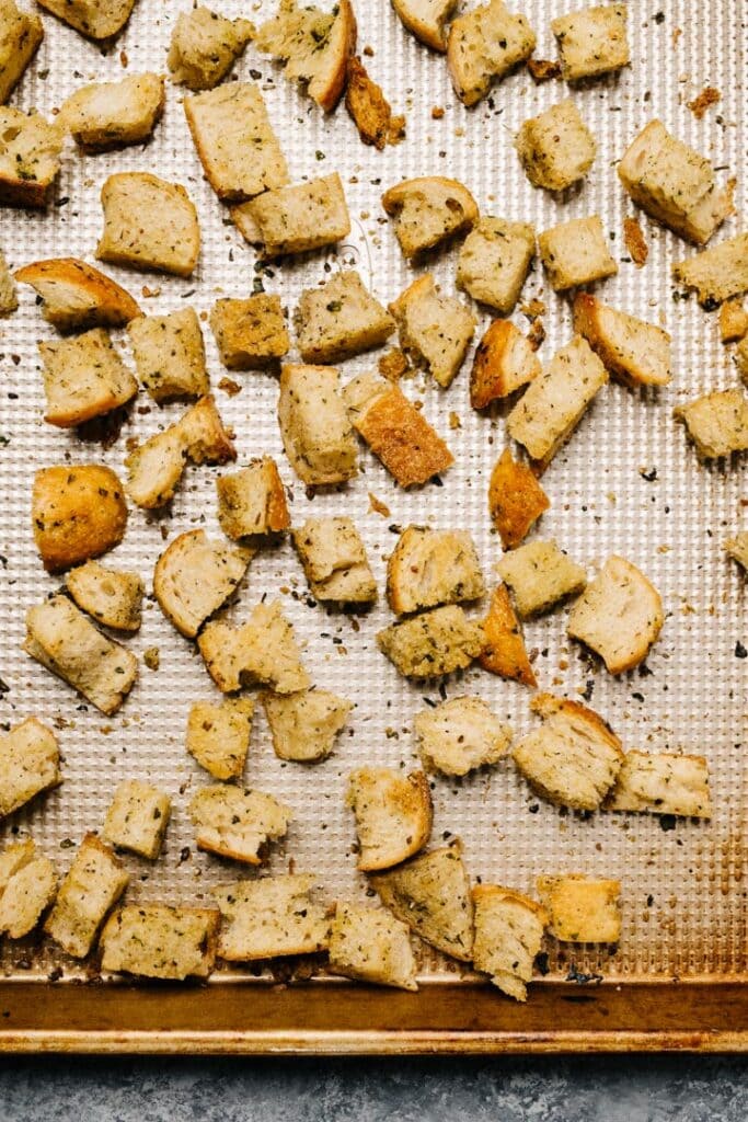 Baked and golden homemade herb croutons on a baking sheet. 
