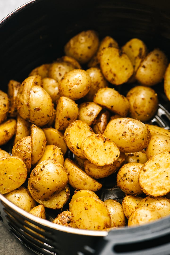 Side view, air fryer potatoes being tossed halfway through cooking.